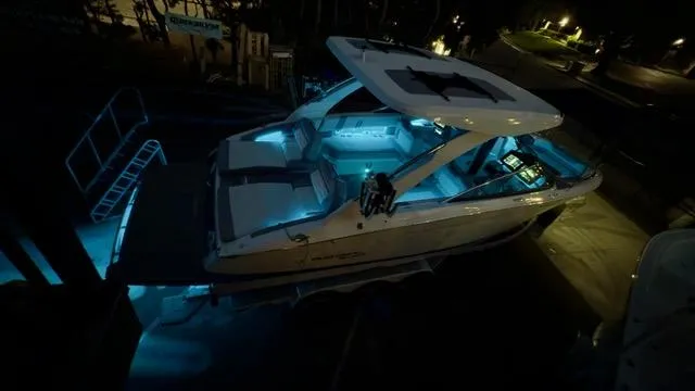 Slide: The Image of 2025 Regal LS9 Surf boat illuminated with blue LED lights at night. - 119