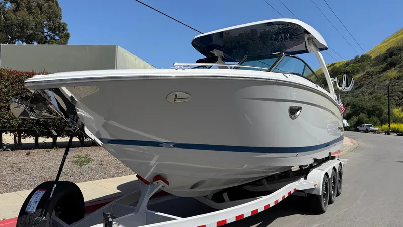 Slide: The Image of 2025 Regal LS9 Surf boat on a trailer, parked outdoors, showcasing sleek design and modern features. - 12