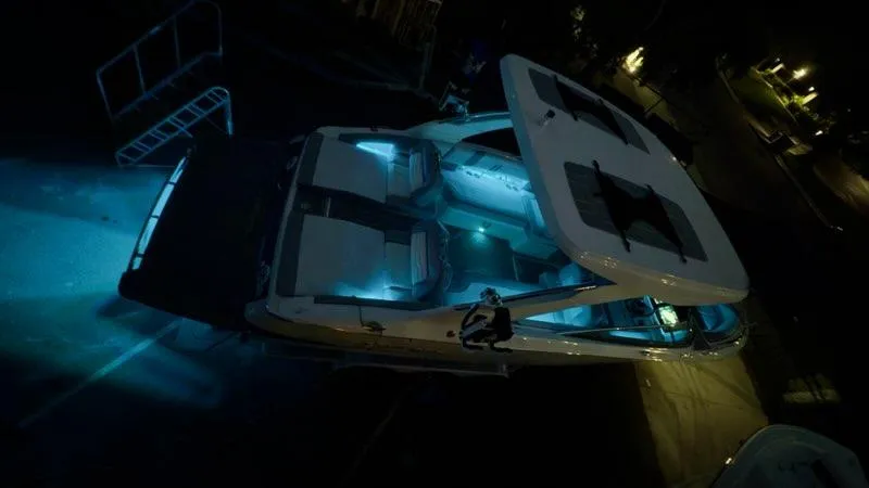 Slide: The Image of 2025 Regal LS9 Surf boat illuminated at night with blue interior lighting. - 120