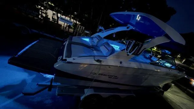 Slide: The Image of 2025 Regal LS9 Surf boat with blue LED lights, parked at night. - 121