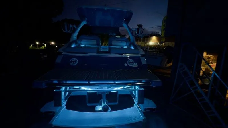 Slide: The Image of 2025 Regal LS9 Surf boat illuminated at night with blue underwater lights. - 124