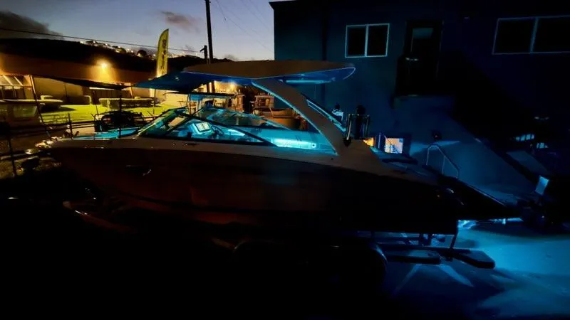 Slide: The Image of 2025 Regal LS9 Surf boat illuminated at night in a marina setting. - 125