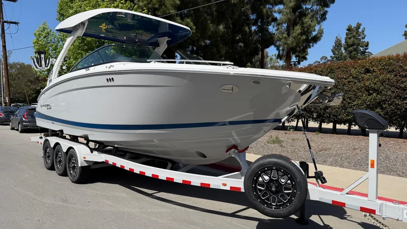 Slide: The Image of 2025 Regal LS9 Surf boat on trailer, parked on street, sunny day. - 15