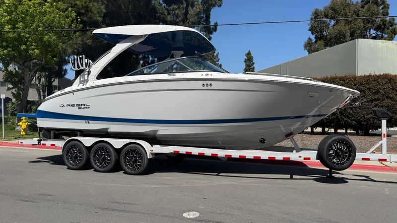 Slide: The Image of 2025 Regal LS9 Surf boat on trailer, parked on street, side view. - 16