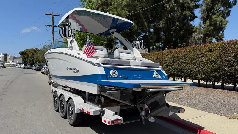 Slide: The Image of 2025 Regal LS9 Surf boat on trailer, parked on street, rear view. - 18
