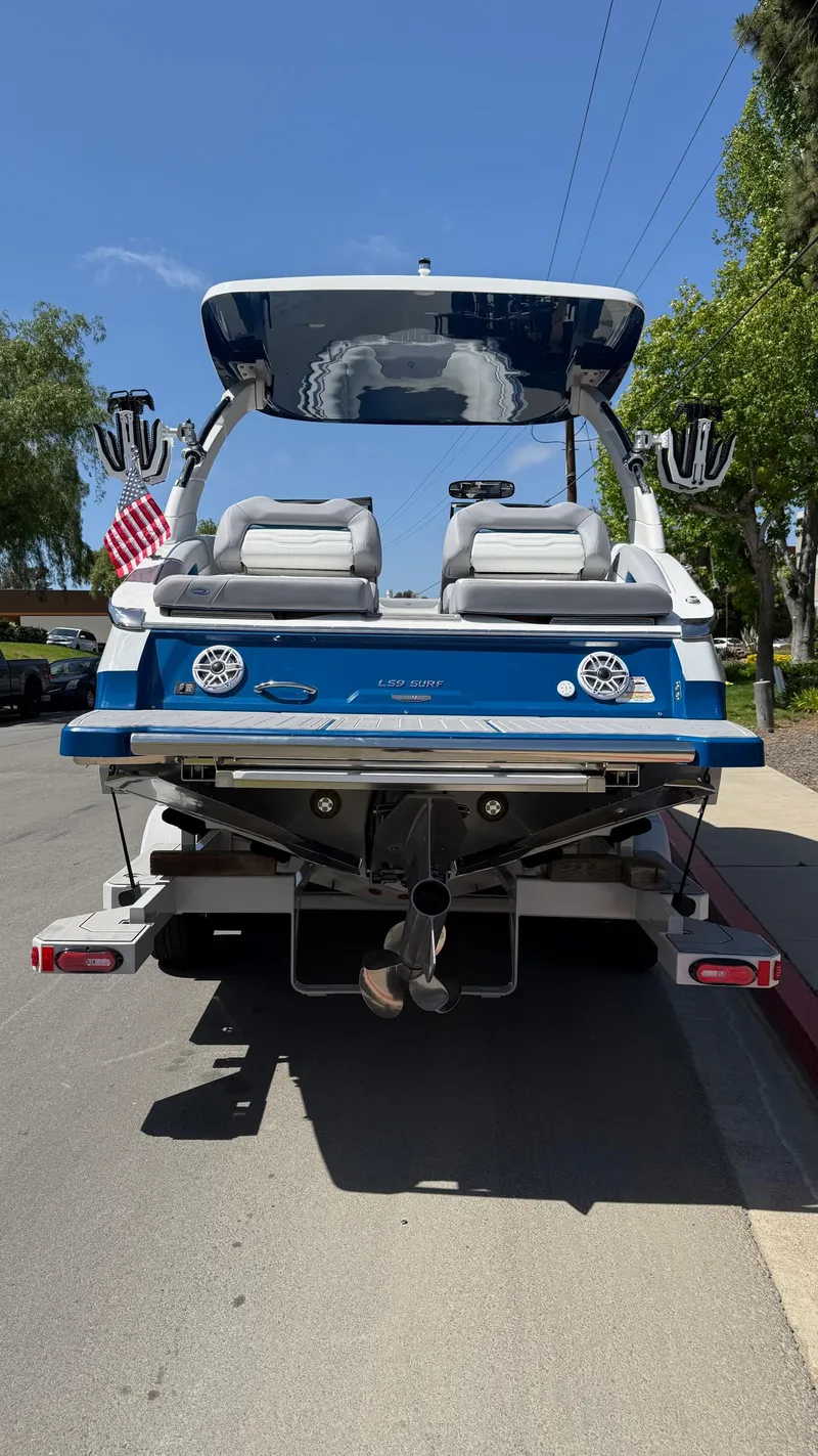 Slide: The Image of 2025 Regal LS9 Surf boat, rear view, parked on street, blue and white design. - 22