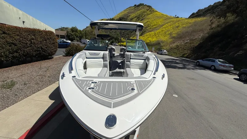 Slide: The Image of 2025 Regal LS9 Surf boat parked on a sunny road with scenic hillside. - 23