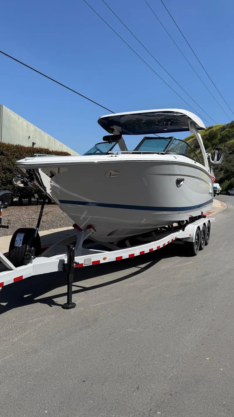 Slide: The Image of 2025 Regal LS9 Surf boat on trailer, parked on a sunny street. - 26