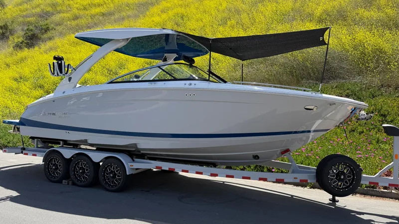 Slide: The Image of 2025 Regal LS9 Surf boat on trailer, parked near vibrant yellow field. - 27