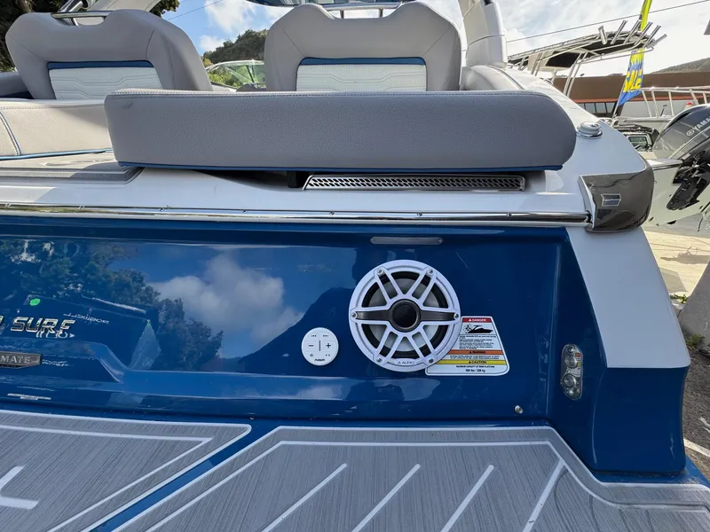 Slide: The Image of 2025 Regal LS9 Surf boat rear view with speaker and seating, docked outdoors. - 35