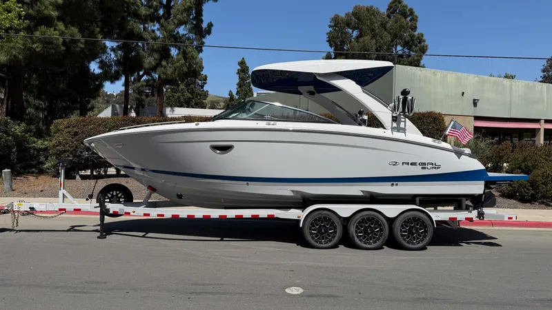 Slide: The Image of 2025 Regal LS9 Surf boat on trailer, parked outdoors, side view. - 4