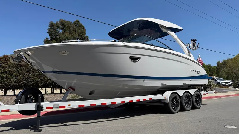 Slide: The Image of 2025 Regal LS9 Surf boat on trailer, parked on street, side view. - 5