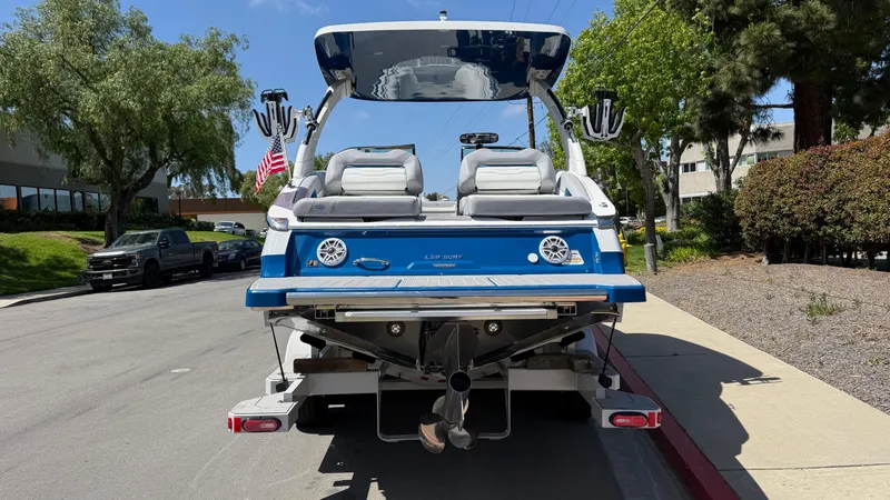 Slide: The Image of 2025 Regal LS9 Surf boat on trailer, parked on street, rear view. - 9