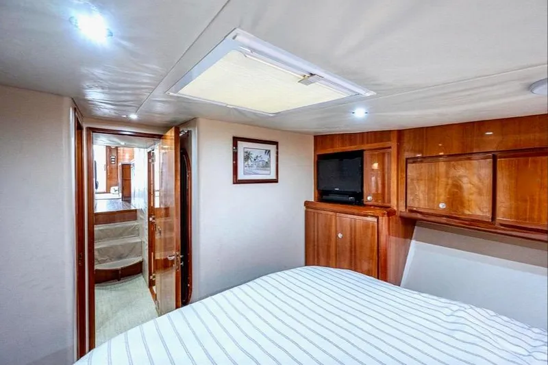 Slide: The Image of Interior of 2001 Bertram 510 Convertible yacht with wood cabinetry and striped bedding. - 22