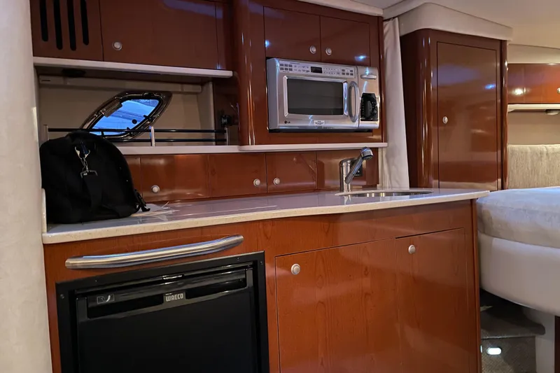 Slide: The Image of 2008 Sea Ray 330 Sundancer interior with kitchenette, featuring microwave, sink, and mini-fridge. - 34