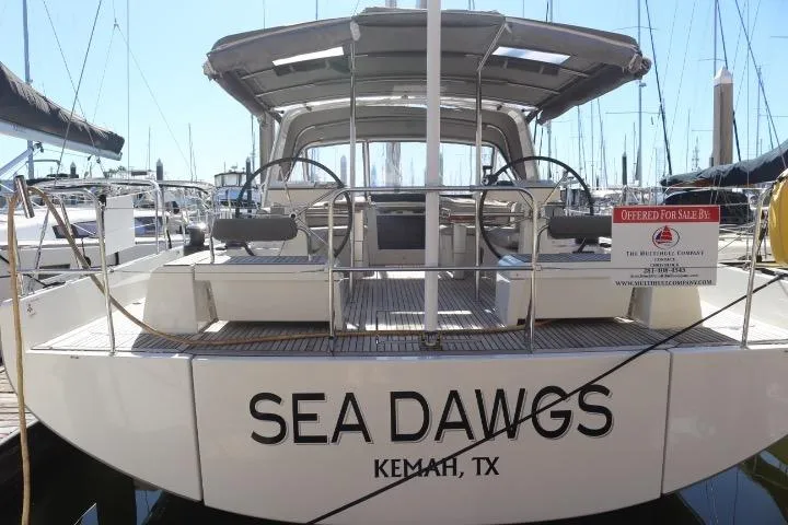 The Image of 2021 Beneteau Oceanis Yacht 54 docked, rear view, overcast sky, "Sea Dawgs" name visible. - 0