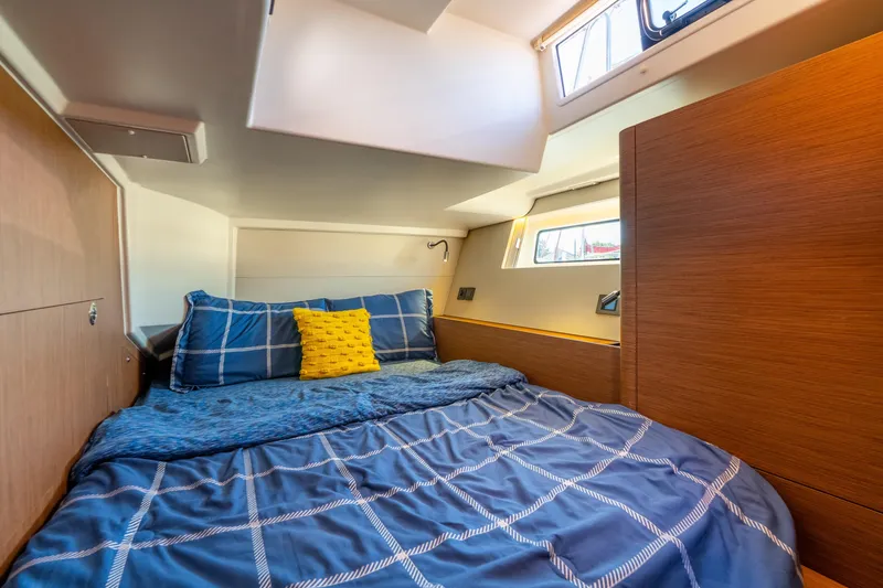 Slide: The Image of Cozy cabin interior of 2021 Beneteau Oceanis Yacht 54 with blue bedding and natural light. - 52