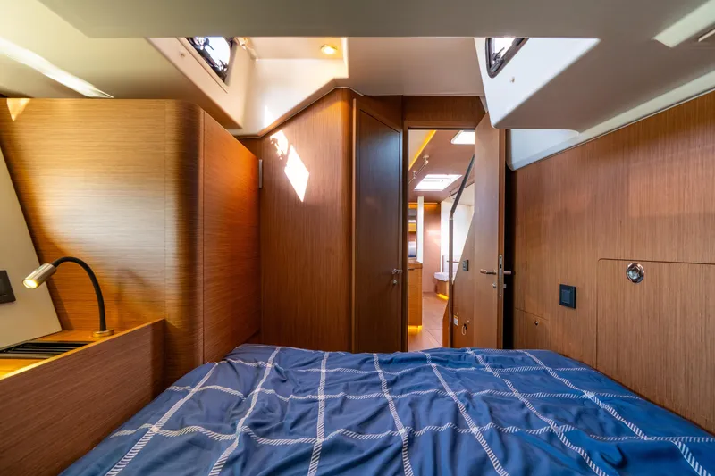 Slide: The Image of Luxurious cabin interior of 2021 Beneteau Oceanis Yacht 54 with wood finish and blue bedding. - 55