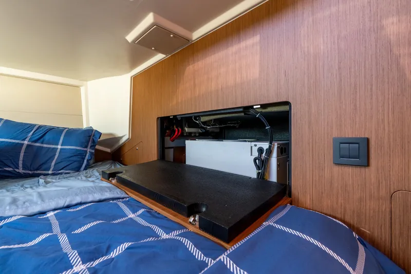 Slide: The Image of Interior of 2021 Beneteau Oceanis Yacht 54 with open storage compartment above bed. - 64