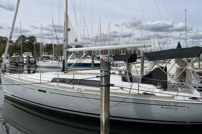 The Image of 2015 Beneteau Oceanis 37 sailboat docked in a marina under clear blue skies. - 0