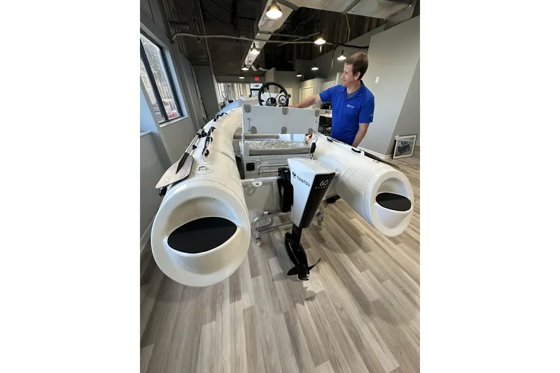 Slide: The Image of 2026 East Marine 320 Electric Tohatsu Alaris boat displayed indoors with a person nearby. - 6