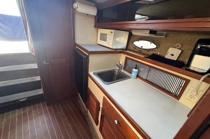 Slide: The Image of 1983 Tiara Yachts 3100 Open interior with seating, table, kitchenette, and stairs. - 22