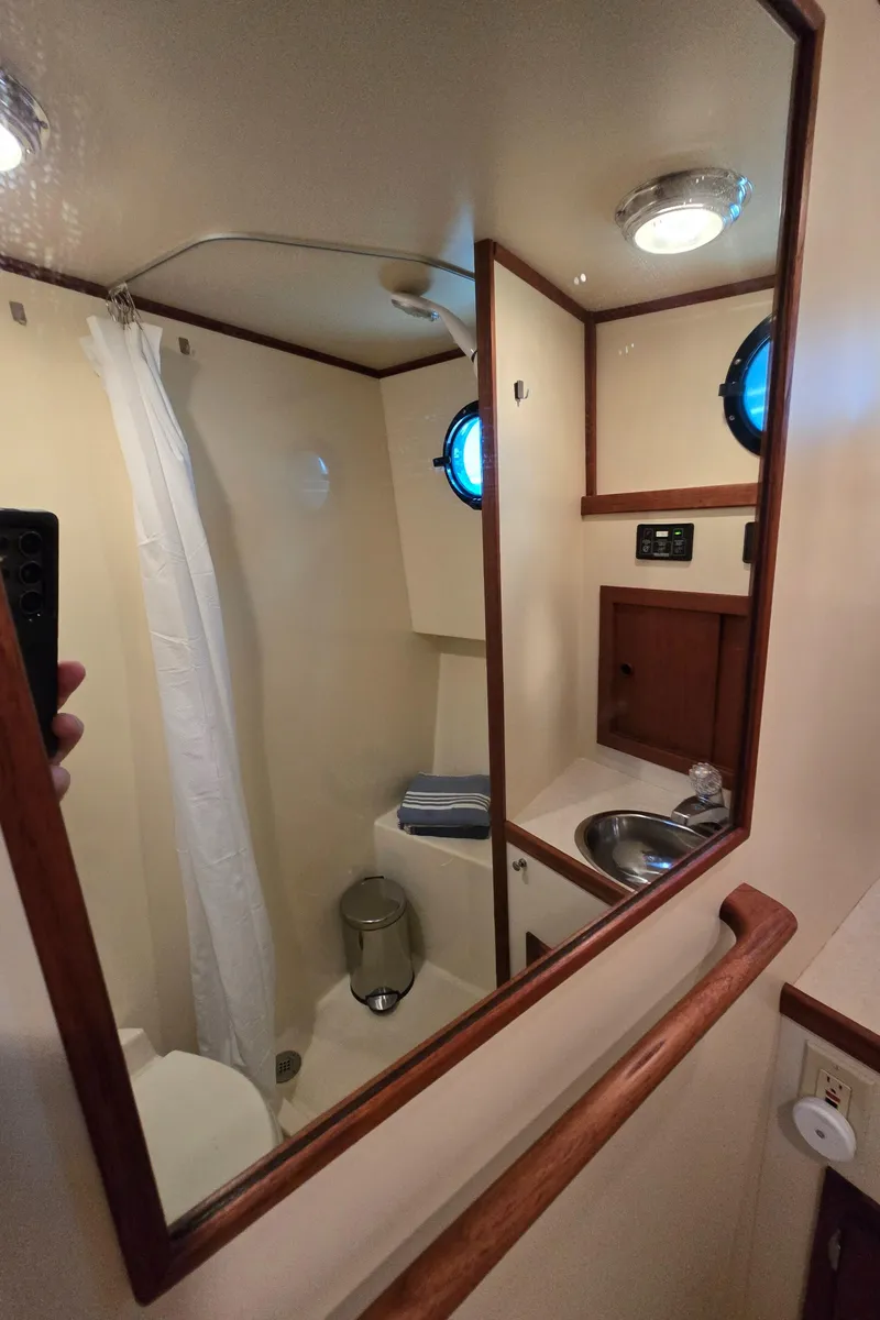 Slide: The Image of Bathroom interior of a 2001 Nordic Tug 32, featuring a shower, sink, and porthole. - 30