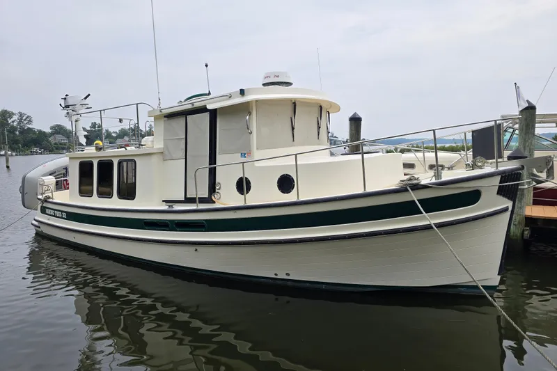 Slide: The Image of 2001 Nordic Tug 32 boat docked in a marina, featuring classic design and green accents. - 4