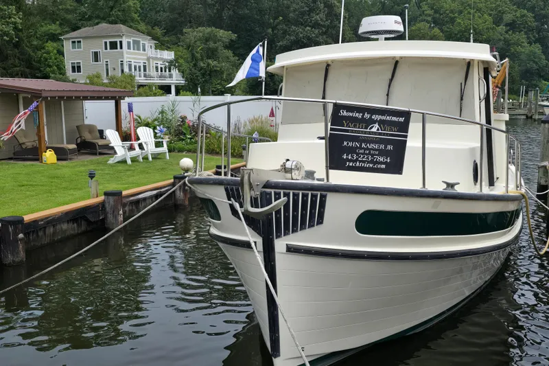 Slide: The Image of 2001 Nordic Tug 32 docked near a waterfront home with lush greenery. - 41