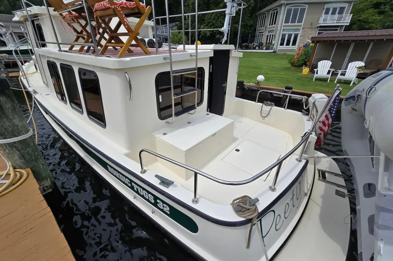 Slide: The Image of 2001 Nordic Tug 32 docked, featuring spacious deck and outdoor seating. - 45