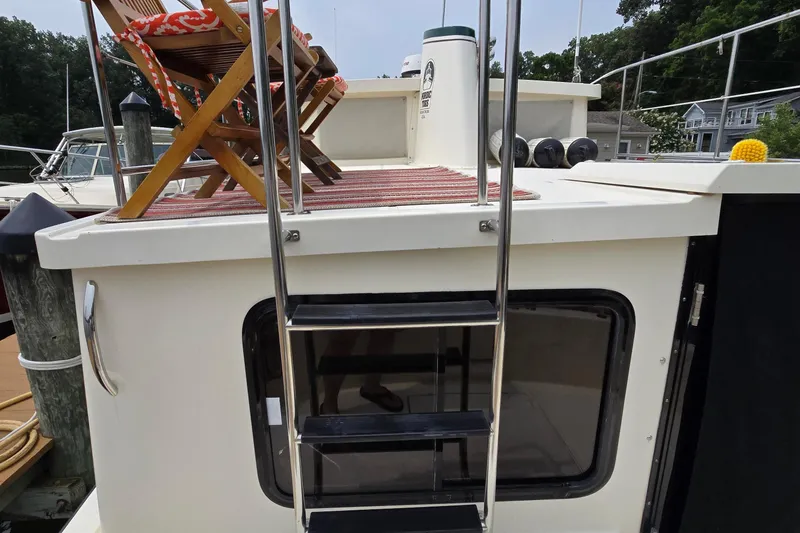 Slide: The Image of 2001 Nordic Tug 32 boat with deck chairs and ladder, docked at marina. - 46