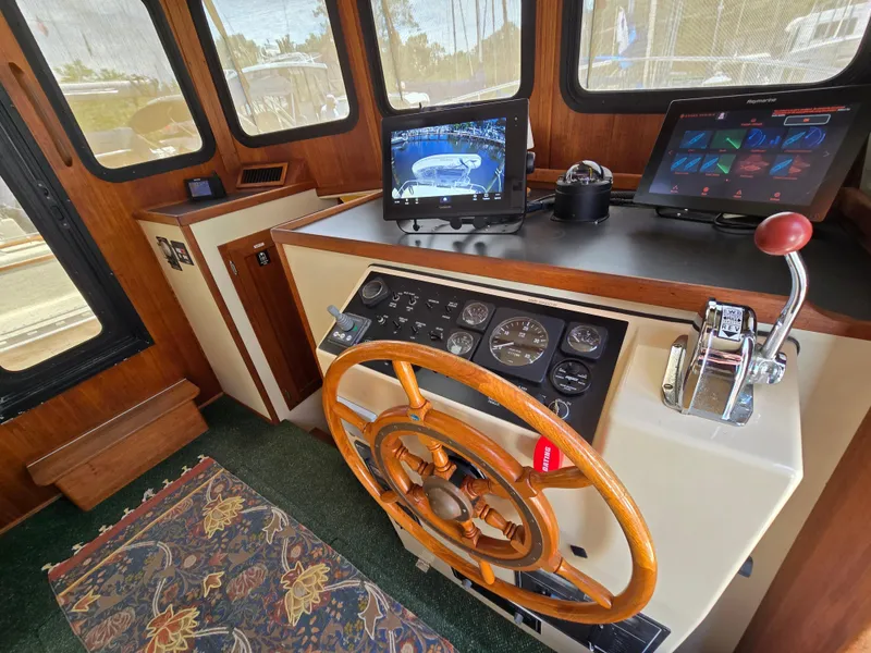Slide: The Image of 2001 Nordic Tug 32 helm with wooden wheel, navigation screens, and control panel. - 7
