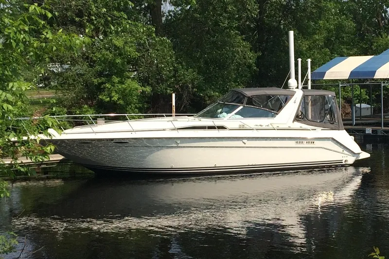The Image of 1992 Sea Ray 370 Sundancer yacht docked on calm water, surrounded by lush greenery. - 0