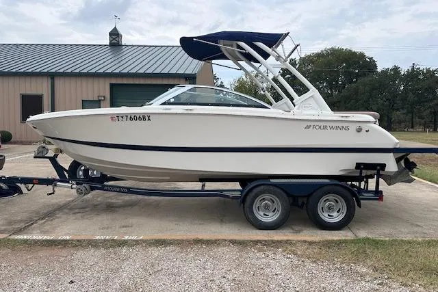 Slide: The Image of 2013 Four Winns H210SS boat on trailer, parked outdoors near a building. - 4