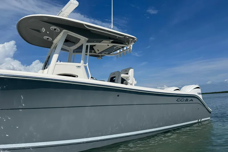 Slide: The Image of 2023 Cobia 280 Center Console boat on calm water under clear blue sky. - 2