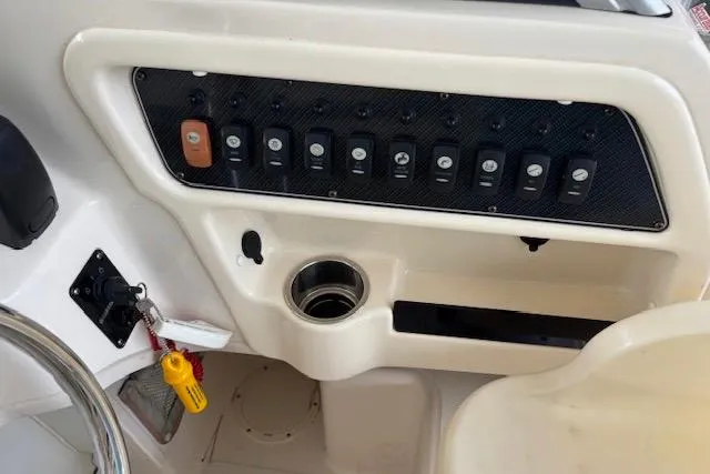 Slide: The Image of Control panel of a 2015 Grady-White Adventure 208 boat with switches and cup holder. - 8