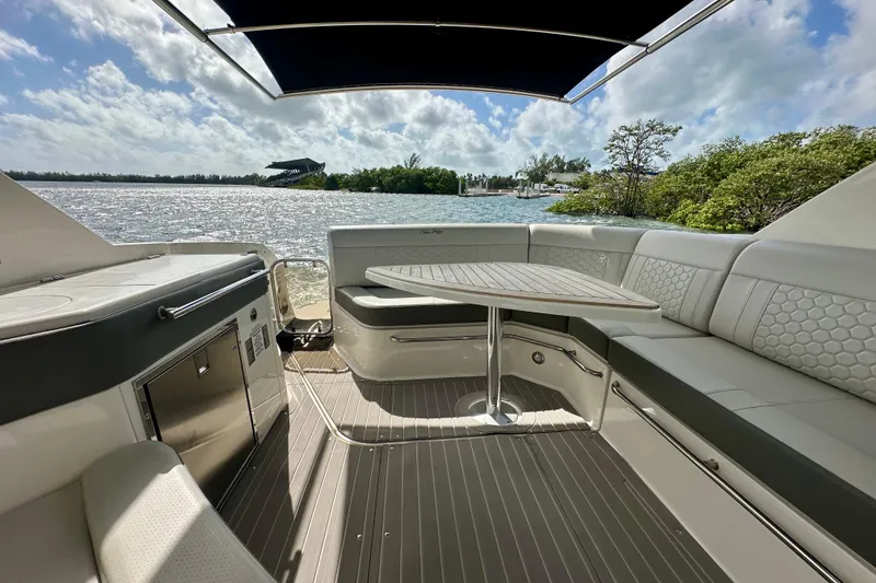 Slide: The Image of 2022 Sea Ray Sundancer 320 Outboard interior with seating and table, overlooking scenic water view. - 23