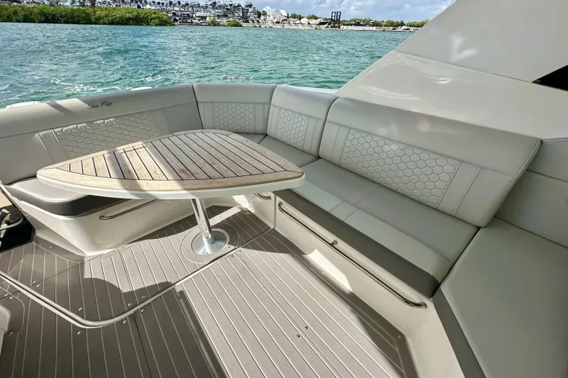 Slide: The Image of 2022 Sea Ray Sundancer 320 Outboard interior with elegant seating and wooden table by the water. - 25