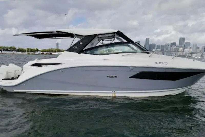 Slide: The Image of 2022 Sea Ray Sundancer 320 Outboard cruising on water with city skyline backdrop. - 3