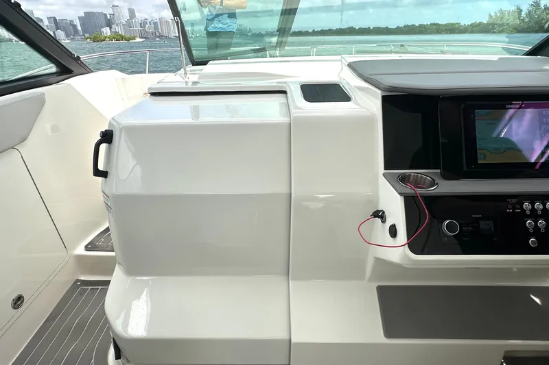 Slide: The Image of 2022 Sea Ray Sundancer 320 Outboard helm with navigation system, docked near city skyline. - 49