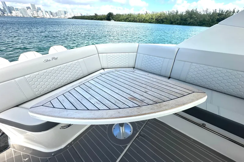 Slide: The Image of 2022 Sea Ray Sundancer 320 Outboard with elegant seating and wooden table, overlooking scenic water. - 58