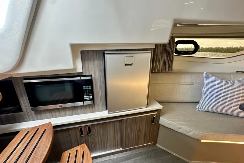 Slide: The Image of Interior of 2022 Sea Ray Sundancer 320 Outboard with microwave, fridge, and seating area. - 63