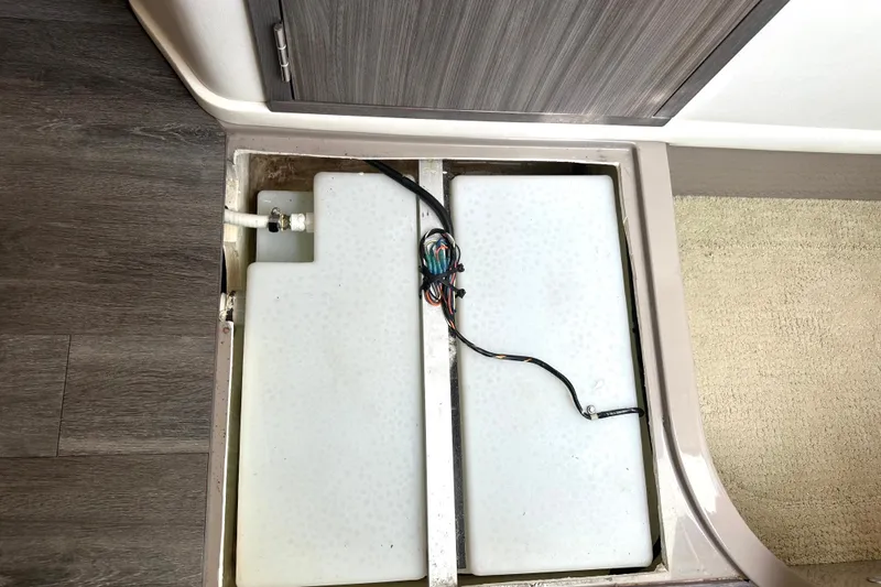 Slide: The Image of 2022 Sea Ray Sundancer 320 Outboard storage compartment with wiring and white tank. - 76