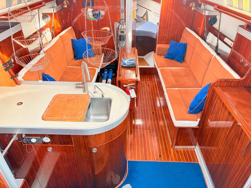 Slide: The Image of Beneteau 38 sailboat cockpit with wooden hatch, blue ropes, and sunny marina view. - 25