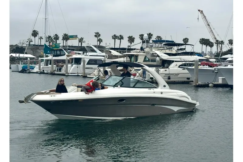 Slide: The Image of 2008 Sea Ray 290 SLX boat cruising in a marina with palm trees and yachts. - 3