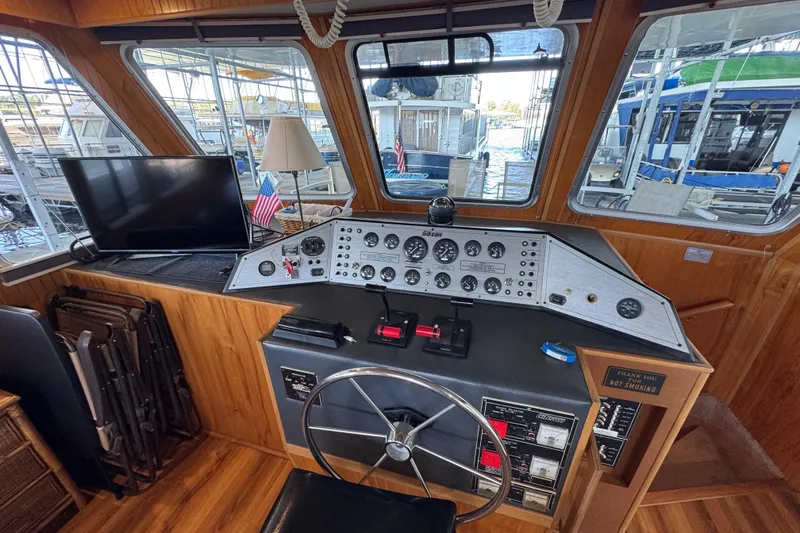 Slide: The Image of 1993 Gibson 44 Cabin Yacht helm with steering wheel, control panel, and dockside view. - 10