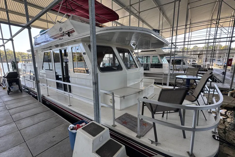 Slide: The Image of 1993 Gibson 44 Cabin Yacht docked in a marina, featuring outdoor seating and covered roof. - 3