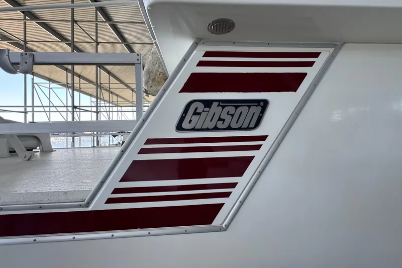 Slide: The Image of 1993 Gibson 44 Cabin Yacht with distinctive red and white design under a covered dock. - 4