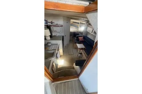 Slide: The Image of 1990 Sea Ray 310 Sundancer cabin interior with seating and kitchenette. - 3