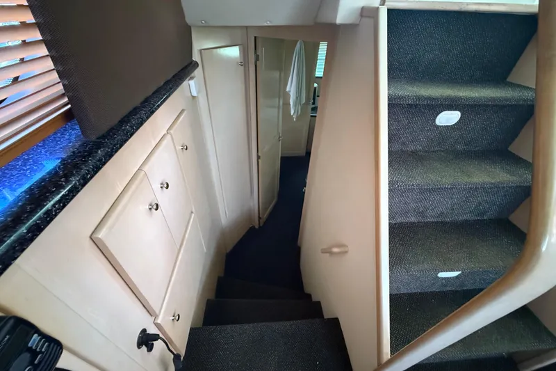 Slide: The Image of Interior stairs of 1999 Carver 406 Aft Cabin Motor Yacht, featuring carpeted steps and storage cabinets. - 22